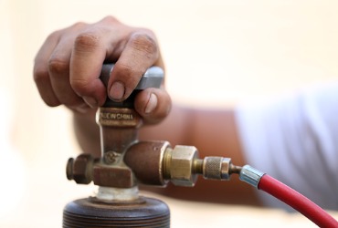 A service man from one of the best Propane Companies in Peoria IL adjusting the valve on a propane tank