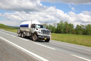 propane tanker truck driving down highway making a delivery