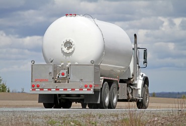 white propane truck driving down the road