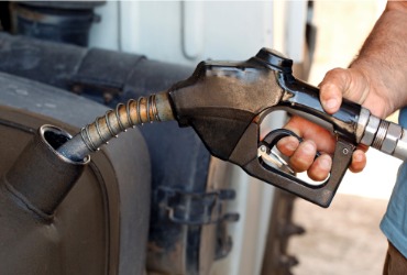 A man filling up a tank of a semi truck with diesel fuel